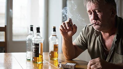 Мужчина пьет сигарету и пьет алкоголь